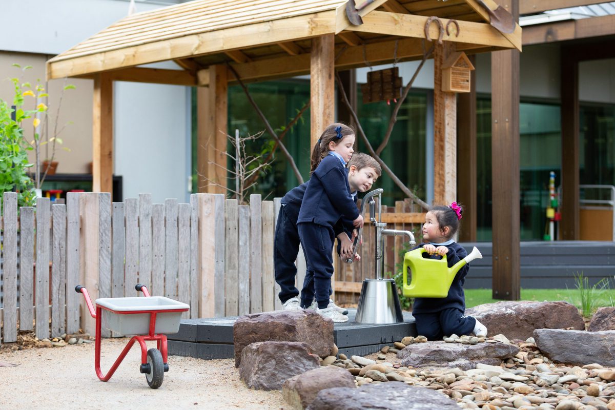 Early learning students playing at the water pump